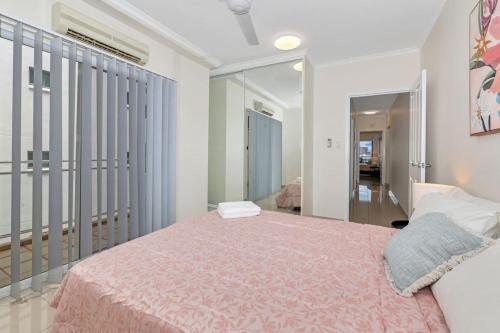 a bedroom with a large bed with a pink blanket at Darwin CBD stunner in Darwin