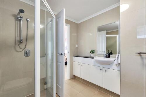 Un baño blanco con lavabo y ducha. en Darwin CBD stunner, en Darwin