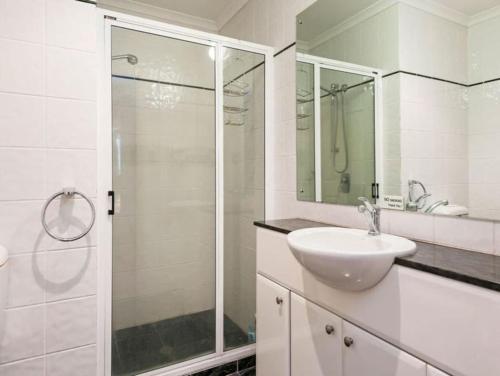 a white bathroom with a sink and a shower at Darwin Esplanade Walk to Waterfront Wines and Waves in Darwin