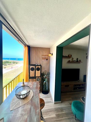 - un salon avec une table et une vue sur la plage dans l'établissement Vue mer wifi parking gratuit plage, au Barcarès