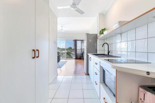a white kitchen with a sink and a counter at Watch the Sun set over Cullen Bay Marina and Harbour in Larrakeyah