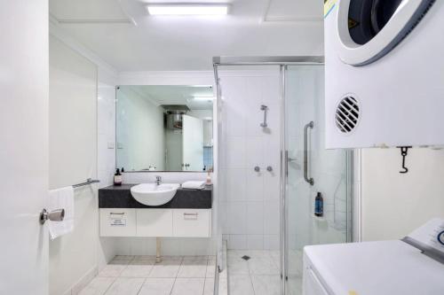 a white bathroom with a sink and a shower at Watch the Sun set over Cullen Bay Marina and Harbour in Larrakeyah