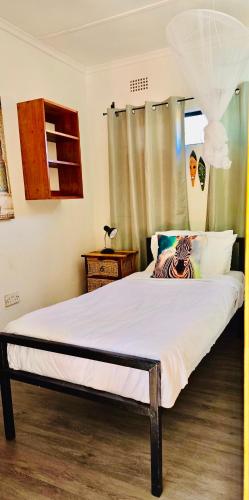 a bedroom with a bed with a zebra pillow on it at Victoria Falls Backpackers Zambia in Livingstone