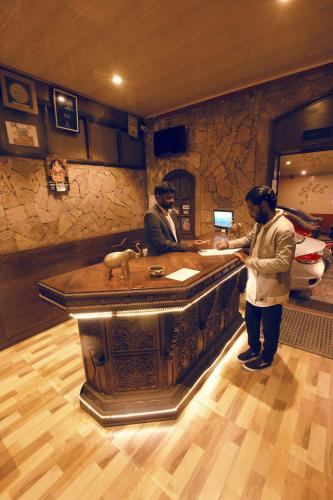 two men standing at a bar in a room at Devi Enterprises - Hotel Khems in Ooty