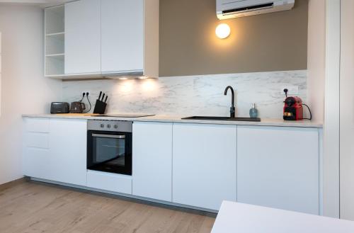 une cuisine blanche avec des armoires blanches et un évier dans l'établissement Cœur de Metz Balnéo - La Suite 4, à Metz