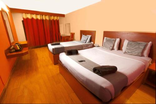 two beds in a hotel room with at Devi Enterprises - Hotel Khems in Ooty