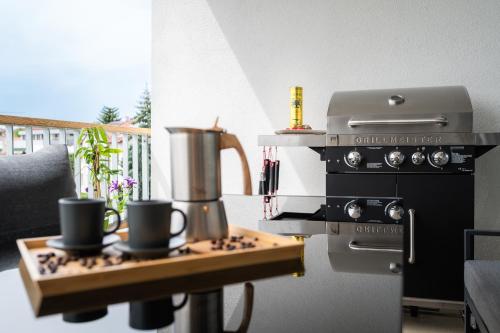 a kitchen with a stove with two cups on a table at Fully equipped Apartments with Terraces, Free garage parking, Netflix & AC - by Apartmány Šlapanice cz in Šlapanice