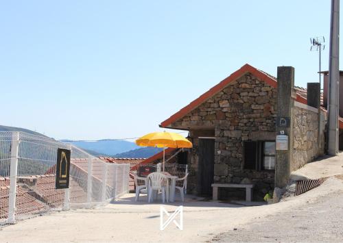 a building with a table and a yellow umbrella at Sobrado Fonseca in Paredes do Rio