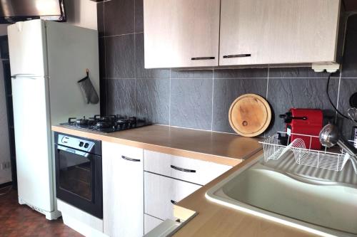 une cuisine avec des armoires blanches, un évier et une cuisinière dans l'établissement Nice T3 with balcony and sea view, au Barcarès