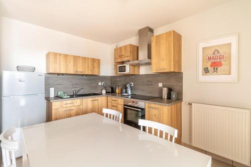 Il comprend une cuisine équipée d'une table blanche et d'un réfrigérateur blanc. dans l'établissement Nice T2 with a large furnished balcony in Toulouse, à Toulouse