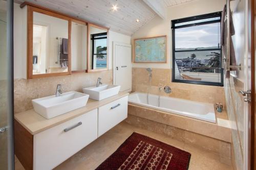 a bathroom with two sinks and a tub and a window at Hermanus Luxury Penthouse in Hermanus
