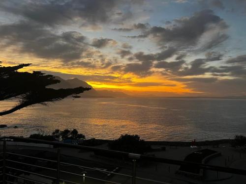 a sunset over the water with a beach and the ocean at Hermanus Luxury Penthouse in Hermanus