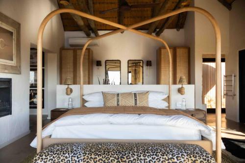 a bedroom with a large white bed with a wooden canopy at Nambiti Hills in Nambiti Private Game Reserve