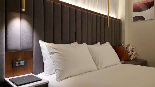 a bed with a black headboard and white pillows at The Plain Hotel Dongyang in Okcheon