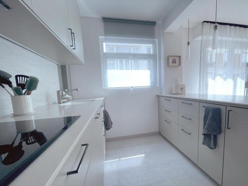 une cuisine blanche avec des comptoirs blancs et une fenêtre dans l'établissement Dolce Vita - Calme et central - Trocadero, à Paris