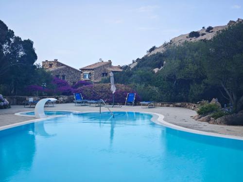 a swimming pool with blue chairs and a mountain at Vista Smeralda in Porto Rotondo