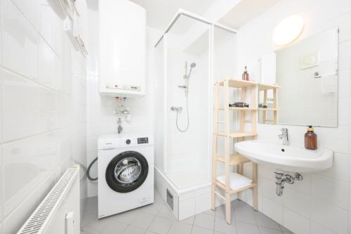 a white bathroom with a washing machine and a sink at Cozy Kunsthaus GRAZ in Graz