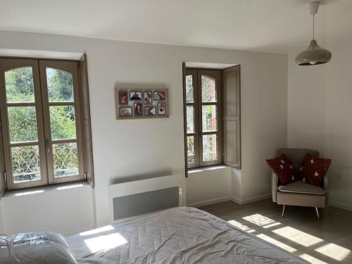 - une chambre avec un lit, 2 fenêtres et une chaise dans l'établissement Maison de charme à Josselin, à Josselin