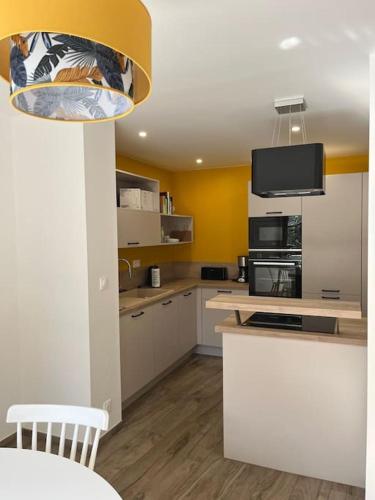 une cuisine avec des armoires blanches et un four à plaques de cuisson dans l'établissement Maison de charme à Josselin, à Josselin