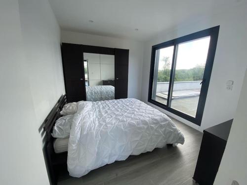 une chambre avec un lit blanc et une grande fenêtre dans l'établissement Maison Contemporaine, à Villez-sous-Bailleul