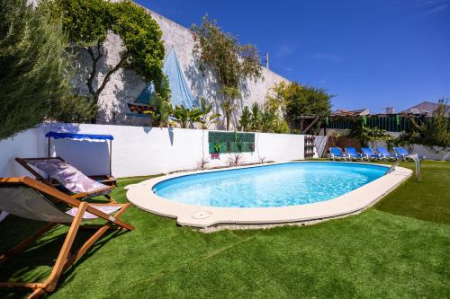 a swimming pool in a yard with chairs and a fence at Meco´s Village in Aldeia do Meco