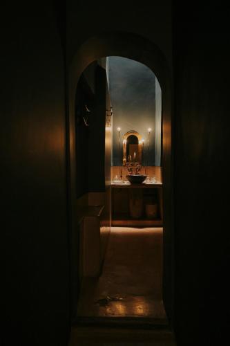a dark bathroom with a sink and a mirror at Dar El Qadi in Marrakech