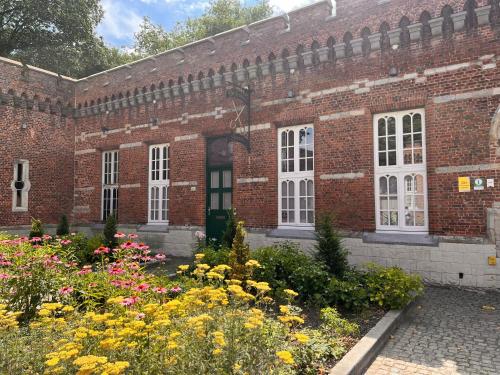 a brick building with flowers in front of it at Vakantiewoning De Gulden Sleutels in Kruibeke
