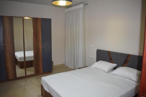 Un dormitorio con una cama blanca y un espejo. en Whispering Waters Two Bedroom with a Garden Azha, en Ain Sokhna