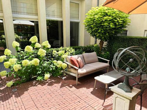 a patio with a chair and flowers and an umbrella at Dukes' Arches Brugge - by Dukes' Hotel Collection in Bruges