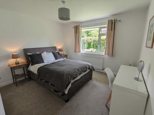 a bedroom with a bed and a desk and a window at Peaceful Glastonbury Bungalow - Ideally Located in Glastonbury