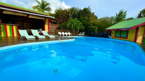 a large swimming pool with chairs and a house at Gites LES CALEBASSIERS in Deshaies