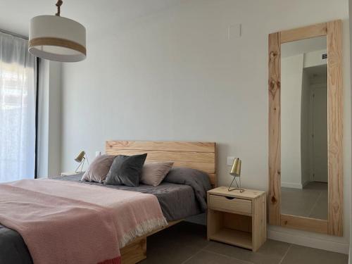ein Schlafzimmer mit einem Bett und einem Tisch mit einer Lampe in der Unterkunft Disfruta del mar a unos pasos in Grao de Castellón