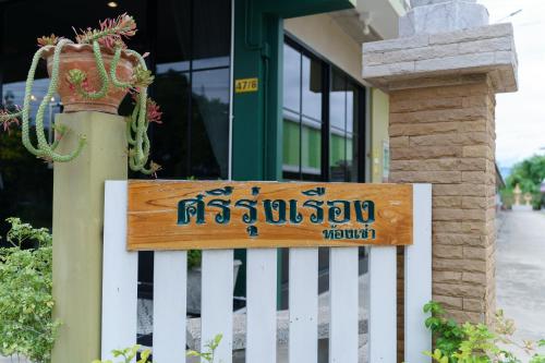 a sign on a white fence in front of a building at SriRungRueng Place in Kanchanaburi