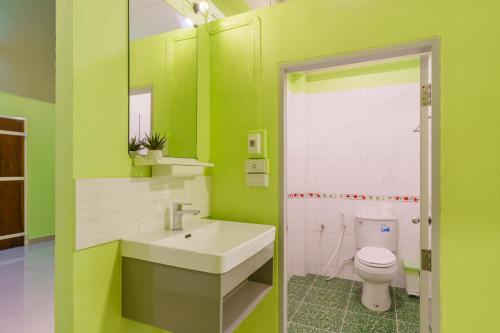 a green bathroom with a sink and a toilet at SriRungRueng Place in Kanchanaburi