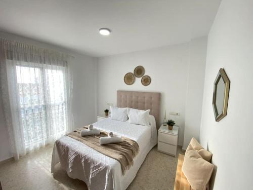 ein weißes Schlafzimmer mit einem großen Bett und einem Spiegel in der Unterkunft Apartamento Malandar in Sanlúcar de Barrameda