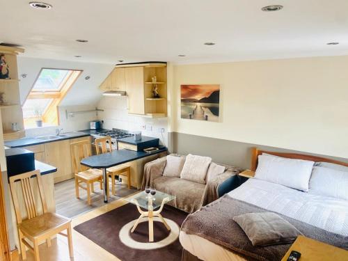 a small living room with a couch and a kitchen at Quaint studio flat in Harrow in Harrow on the Hill