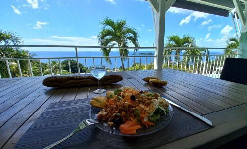 a plate of food on a table with a glass of wine at Logements Vue Mer accès piscine en Guadeloupe in Bouillante
