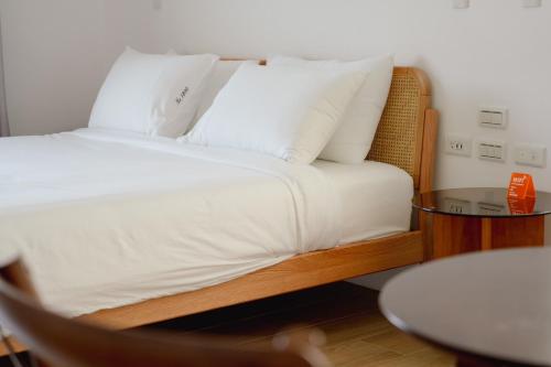 a bedroom with a bed with white sheets and a table at No.1899 House in Meinong