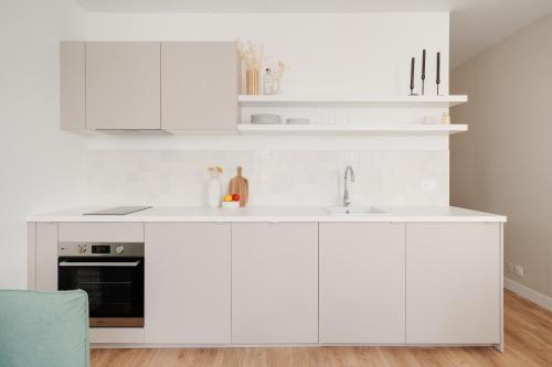 une cuisine blanche avec des armoires blanches et un évier dans l'établissement Le Coquet des Trois-Maisons avec parking privatif, à Nancy