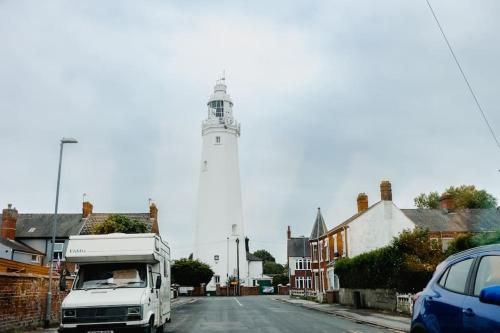 a white truck driving down a street with a lighthouse at Withernsea Coastal Getaway 2 bed Apt in Withernsea