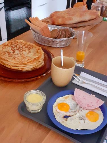 ein Tisch mit einem Teller mit Eiern, Pfannkuchen und Brot in der Unterkunft La Belle Maison in Avèze