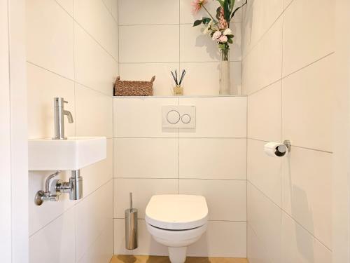 a white bathroom with a toilet and a sink at Vakantiehuis DO52 centrum Domburg in Domburg