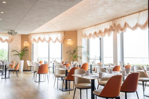a restaurant with tables and chairs and large windows at Garda Hotel Forte Charme in Nago-Torbole