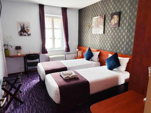 a hotel room with two beds and a desk at Hôtel du Fort in Meulan