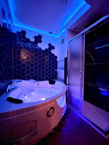 La salle de bains est pourvue d'une baignoire et de lumières bleues. dans l'établissement GI-AZ Love room, à Bondy