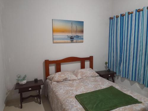 a bedroom with a bed and two tables and a picture at Casa na praia em São Sebastião in São Sebastião