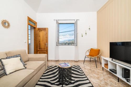 a living room with a couch and a television at Sunset House in Ribeira Brava