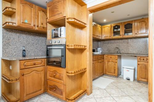 a kitchen with wooden cabinets and a stove at Sunset House in Ribeira Brava