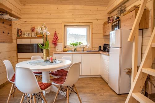a kitchen with a white table and chairs at Milkės Karibai - poilsio namelis su sauna ir kubilu in Statiškė