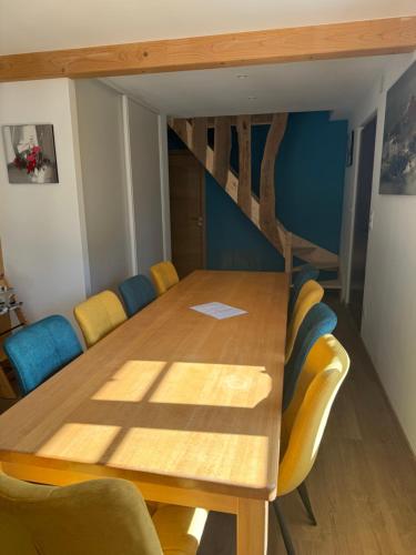 a dining room with a wooden table and yellow chairs at Au Jardin de Mamie in Lembach